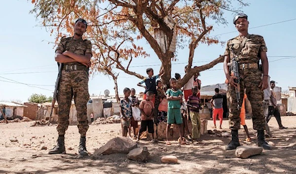 Troops of the Ethiopian Army stand in fromt of children in the Mai Aini Refugee Camp, Ethiopia. (AFP)