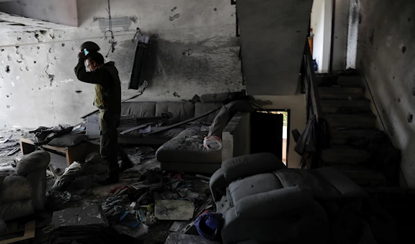 An Israeli soldier from the IOF Spokesperson's Unit inspects the damaged house after it was hit by a rocket fired from the Gaza Strip, in Askalan, occupied Palestine, May 20, 2021 (AP)