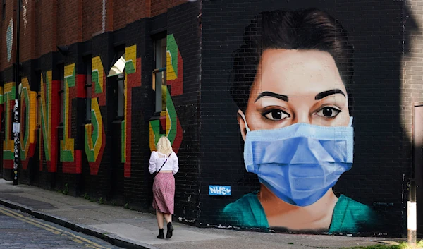 A woman walks past a mural depicting a nurse wearing a protective mask in Shoreditch, amid the coronavirus disease (COVID-19) outbreak, in London, Britain April 21, 2020. (AP)