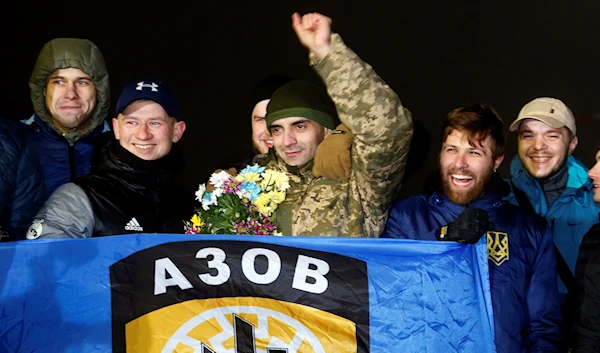 A released Ukrainian prisoner with officers of the Azov Battalion stand around him holding the Azov flag in Kiev Boryspil Airport, Ukraine, December 28, 2017 (AP)