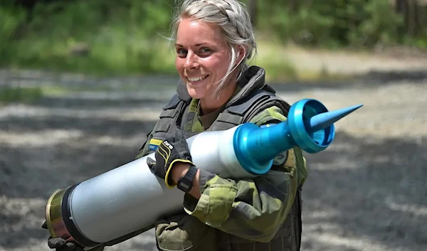 A Swedish loader carries a depleted uranium sabot ammo round 2019 (Public domain)