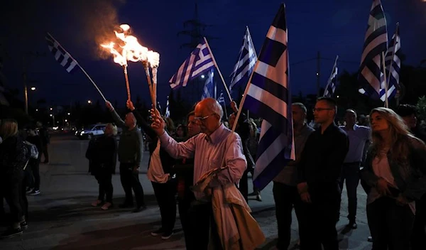 Supporters of Golden Dawn far-right party hold torches and Greek national flags during a rally to commemorate the anniversary of the massacre of Pontic Greeks by the Ottoman empire at the end of the first world war, in Athens, Greece May 19, 2019 (Reuters)