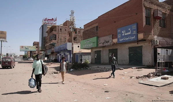 People walk past shuttered shops in Khartoum, Sudan, Tuesday, April 18, 2023 (AP)