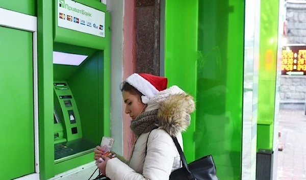 A woman wearing a Santa hat  uses an ATM machine belonging o Ukraine's largest bank PrivatBank, Kiev, Ukraine. (AFP)