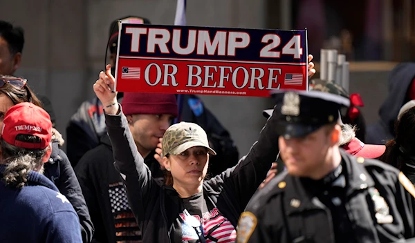 A protester holds a sign near Trump Tower, before the former president arrived, in New York on Monday, April 3, 2023 (AP Photo/Bryan Woolston)