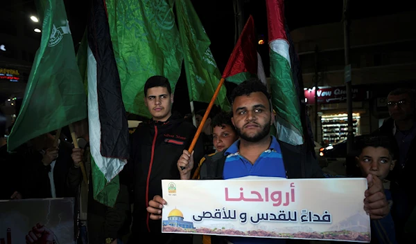 Palestinians wave Palestinian national flags during a protest against an Israeli police raid on Al-Aqsa Mosque compound in the Old City of Al-Quds early Wednesday, at the main square in Gaza City, occupied Palestine (AP)