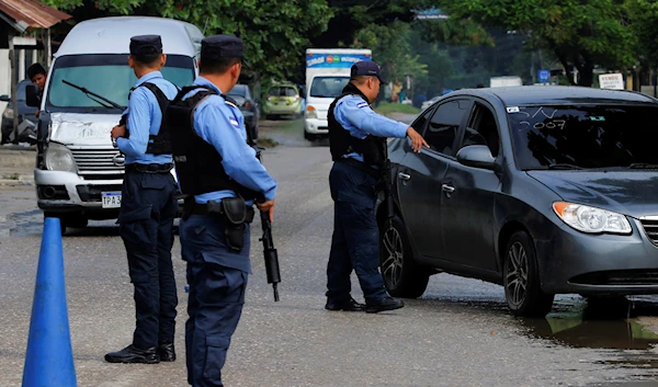 Police inspect cars at a checkpoint in the neighborhood of Rivera Hernandez in San Pedro Sula, Honduras, December 7, 2022 (AP)