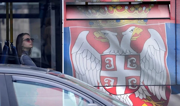 A woman looks out from a bus painted in the colours of the Serbian flag in Belgrade, Serbia, Saturday, May 28, 2022 (AP Photo/Darko Vojinovic)