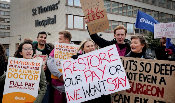 Junior doctors hold placards as they stand at a picket line outside St Thomas' Hospital in Westminster, London, Monday, March 13, 2023 (AP)