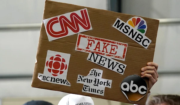 sign showing major news organizations along with the words "fake news" is held up as U.S. President Donald Trump speaks at a Make America Great Again Rally in Washington, Michigan April 28, 2018 (Reuters)