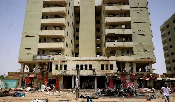 A man walks near a damaged car and buildings at the central market during clashes between the paramilitary Rapid Support Forces and the army, in Khartoum, Sudan, on April 27, 2023 (Reuters)