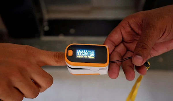 A medical worker (R) puts a pulse oximeter on a woman's finger to check her oxygen level, in India June 26, 2020. (Reuters)