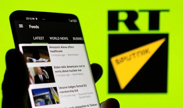 RT app is seen on a smartphone in front of RT and Sputnik logo. (Reuters)