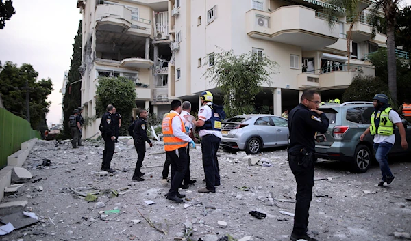 Israeli rescue workers inspect a damaged house after it was hit by a rocket fired from the Gaza Strip, in 'Rehovot', occupied Palestine, May 11, 2023 (AP)