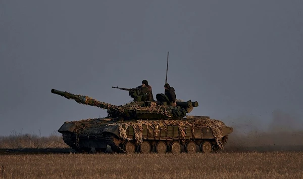 Ukrainian soldiers ride atop a tank on the frontline in Bakhmut, Donetsk region, Wednesday, March 22, 2023 (AP Photo/Libkos)