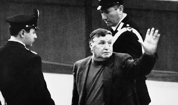 Salvatore Toto Riiana, the reputed boss of bosses of the Sicilian Mafia, waves as he is taken away from Court by two carabinieri (para-military police) after his third appearance in Court, in Palermo, on March 4, 1993. (AP)