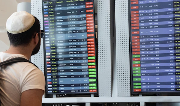 Passengers look at the monitor displaying delayed flights at Ben Gurion airport, near Tel Aviv, Occupied Palestine, Monday, March 27, 2023. (AP)