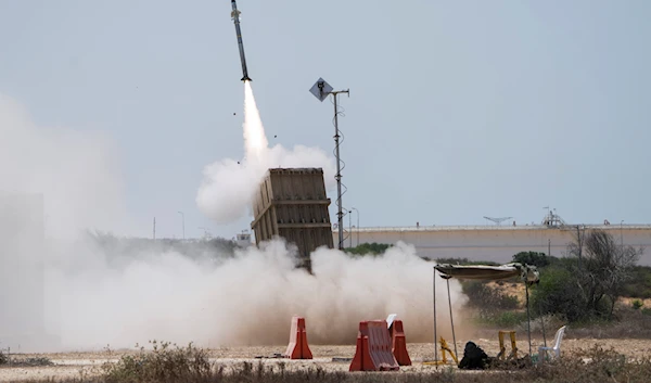 An Israeli soldier takes cover as an Iron Dome air defence system launches to intercept a rocket fired from the Gaza Strip, in occupied Askalan, southern occupied Palestine, August 7, 2022 (AP)