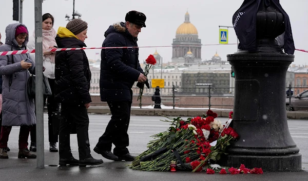 People lay flowers near the side of an explosion at the 'Street Bar' cafe with the St. Isaac's Cathedral in the background in St. Petersburg, Russia, April 3, 2023 (AP)