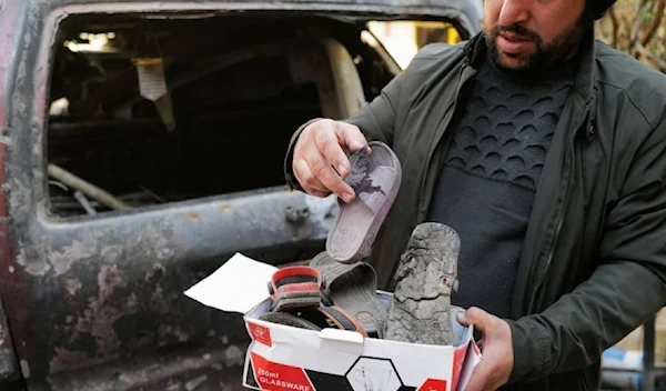 Ajmal Ahmad shows shoes of his nephews, victims of a U.S drone strike that killed 10 civilians, including seven children, as he stands beside a damaged car at the house's courtyard in Khwaja Bughra in Kabul, Afghanistan November 7, 2021. (Reuters)