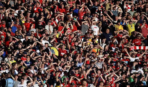 Fans shield themselves from the sun to watch the English Premier League soccer match between Nottingham Forest and Arsenal at City ground in Nottingham, England, May 20, 2023 (AP