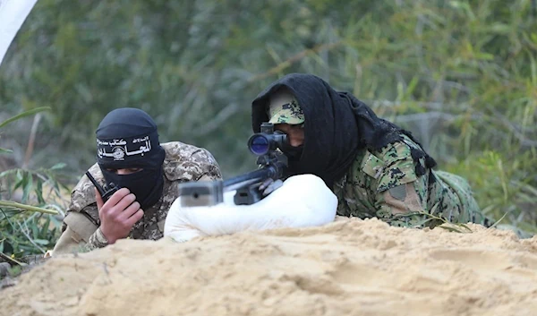 Two fighters of Al-Mujahideen Brigades take aim at targets with a sniper rifle.