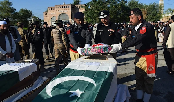 Security officials place flowers on the coffin of a police officer who was killed in an ambush in the village of Shahab Khel in Lakki Marwat, Pakistan, on Nov. 16. (AFP)