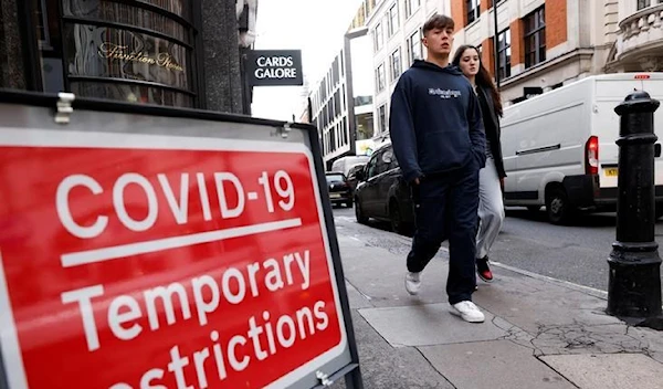 A coronavirus disease (COVID-19) sign is seen as people walk, in the Soho area, in London Britain October 15, 2020. (Reuters)