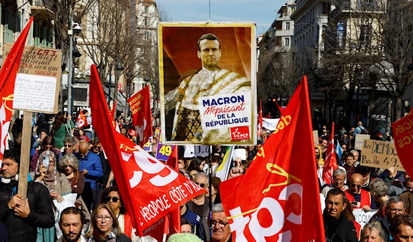 Protesters hold a placard depicting French President Emmanuel Macron as a king during a demonstration as part of nationwide strikes and protests against French government's pension reform in Nice, France, March 28, 2023 (Reuters)