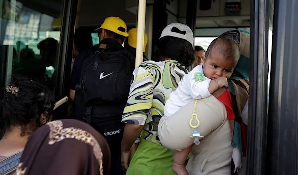 Refugees and migrants get on a bus which transports them to the metro station, after their arrival from the northeastern Greek island of Lesbos to the Athens' port of Piraeus on Monday, Sept. 7, 2015. (AP)