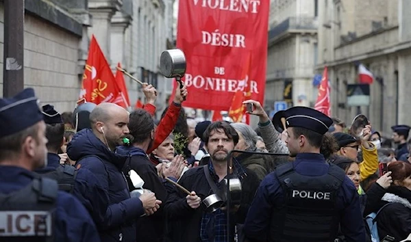 Police officers stand guard as members of the General Confederation of Labour (CGT) trade union and protesters take part in a demonstration against pension reform in Paris on April 24, 2023. (AFP)