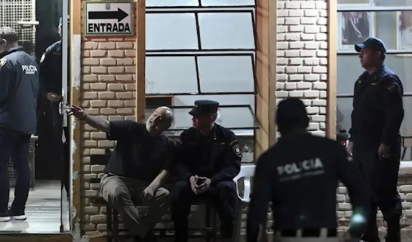 National Crusade Party presidential candidate Paraguayo Cubas, center left, sits next to police Sub Commissioner Baldomero Jorgge, outside the Specialized Group building where Cubas is being held, in Asuncion, Paraguay, Friday, May 5, 2023. (AP)