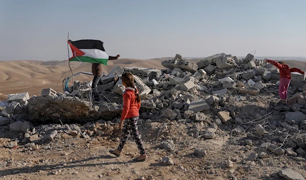 Palestinians stand on the remains of a school after it was demolished by the IDF in the West Bank area known as Masafer Yatta, on November 23, 2022 (AP)