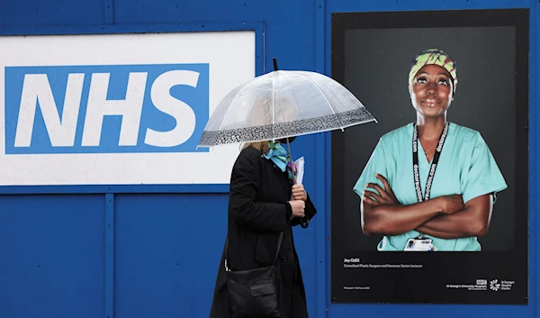 A person walks past an image of a National Health Service (NHS) worker displayed on hoardings outside a temporary field hospital at St George's Hospital, amid the coronavirus disease (COVID-19) outbreak in London, Britain, January 8, 2022. (Reuters)