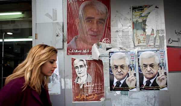 A Palestinian woman walks past posters with pictures of PFLP Secretary-General Ahmed Saadat, who is currently imprisoned by the Israeli occupation, March 19, 2014, in the West Bank city of Ramallah, occupied Palestine (AP)