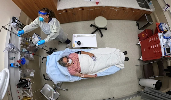 A woman receives an antibody infusion while lying on a bed in a trauma room at the Upper Tanana Health Center Wednesday, Sept. 22, 2021, in Tok, Alaska. (AP Photo/Rick Bowmer)