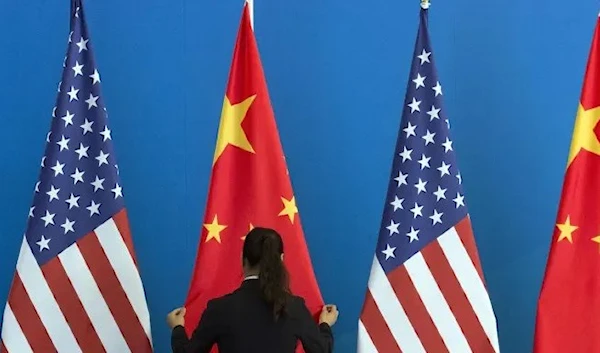 A woman adjusts a Chinese flag near US flags. (AFP)