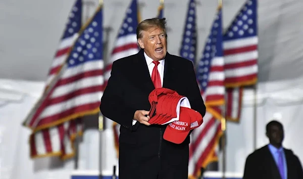 Former US President Donald Trump holds MAGA caps during a rally for Georgia Republican candidates in Columbus, Georgia, US, June 10 2023. (AP)