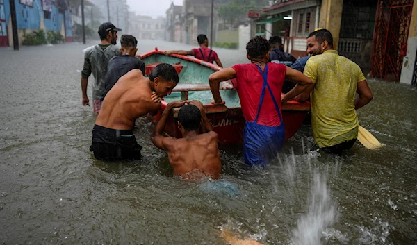 Volunteers push a boat through a street flooded by heavy rains, to go and rescue a neighbor who is unable to leave his home on his own, in Havana, Cuba, Friday, June 3, 2022. (AP)