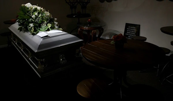 casket topped with a small wreath of flowers (AFP)