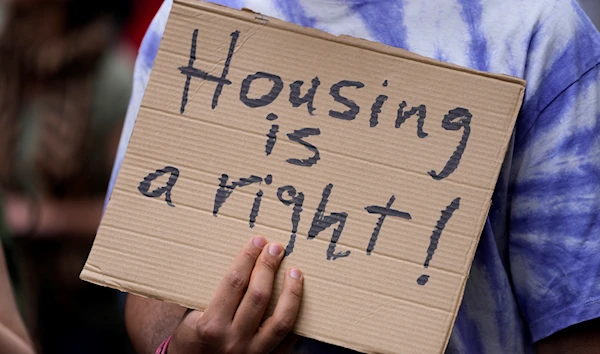 A protestor carries a poster, during a demonstration to demand solutions for Portugal's housing crisis, in Lisbon, Saturday, April 1, 2023. (AP)