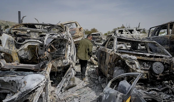 A Palestinian man walks between cars burnt down by Zionist settlers in the town of Huwara, occupied West Bank, Palestine, February 27 2023. (AP)