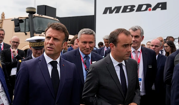 French President Emmanuel Macron, left, flanked by French Defense Minister Sebastien Lecornu visits the International Paris Air Show, Monday, June 19, 2023 in Le Bourget, north of Paris. (AP)