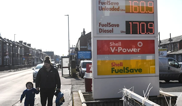 People walk past a board indicating the prices of petrol and diesel fuel at a Shell petrol station, in Manchester, U.K., March 8, 2022. (AFP)