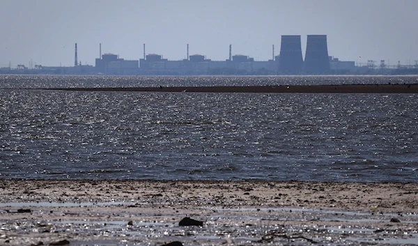 The Zaparozhye nuclear power plant is seen in the background of the shallow Kakhovka Reservoir after the dam collapse, in Energodar, June 9, 2023 (AP)