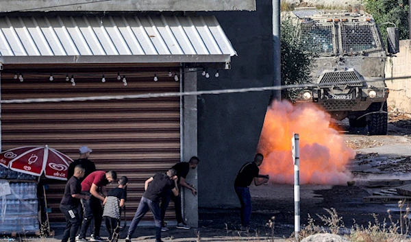 An explosive charge detonates in front an Israeli Armored Personnel Carrier (APC) as local fighter shoot towards it, Jenin, in the occupied West Bank, Palestine, June 19 2023. (AFP)