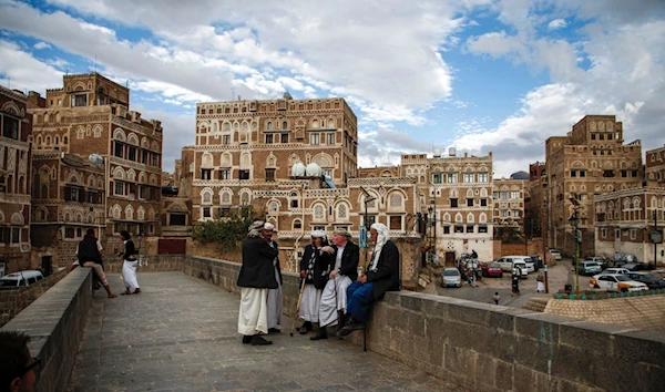 Locals sit and chat by the ledge of a bridge leading to UNESCO-listed buildings in the old city of Sanaa, Yemen, February 15 2017. (AFP)