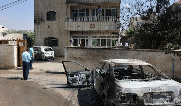 Locals stand by torched vehicles which were set ablaze by settlers who attacked the village of Turmus Aya, occupied West Bank, Palestine, June 21 2023. (AFP)