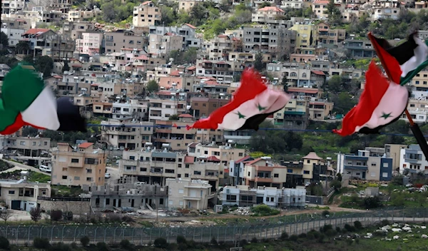 Syrian and Palestinian flags fly in the town of Ain Al-Tineh which overlooks the Israeli occupied town of Majdal Shams in the Golan Heights, Quneitra, Syria, March 26 2019. (AFP)