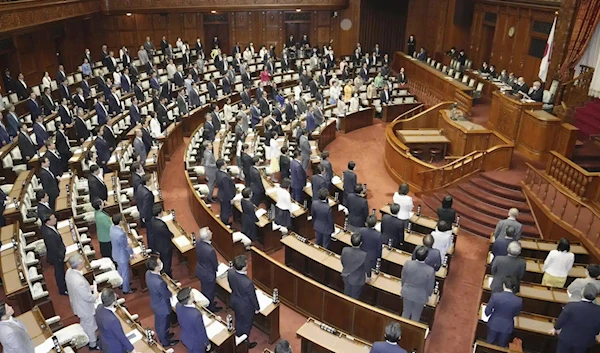 Japanese lawmakers in the upper house stand in Tokyo on June 16, 2023. (Kyodo News via AP)